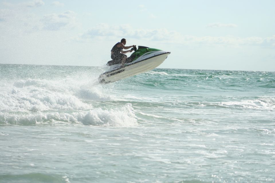 Green and white jet ski jumping a wave with rider over ocean water
