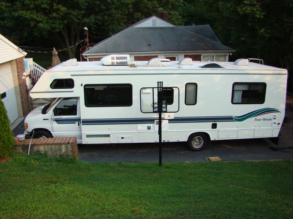 White Four Winds Class C RV parked in a driveway.