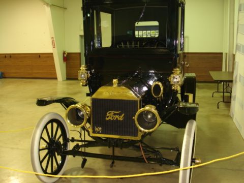 1909 Ford Model T - The front view of a black 1909 Ford Model T with brass accents is displayed indoors. The car features a gold Ford emblem on the radiator an…