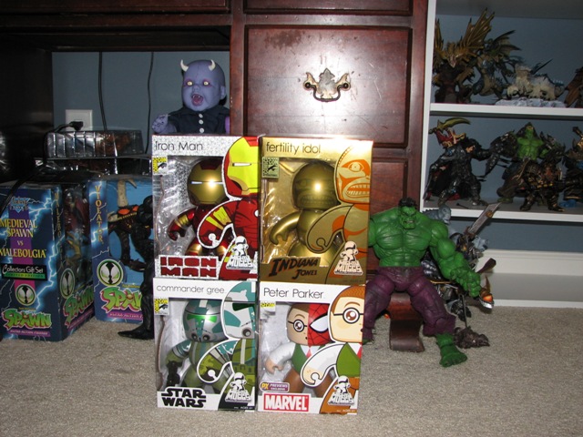 Four boxed vinyl collectible figures on carpet next to a green Hulk figure