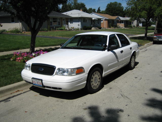 White 2003 Ford Crown Victoria sedan parked on a residential street, front three-quarter view.