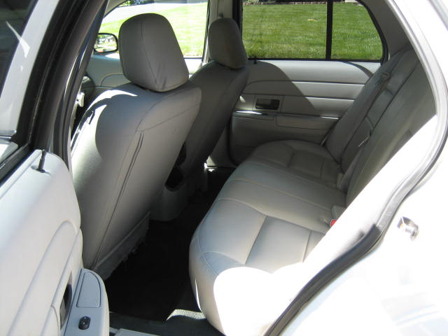 Interior view of a white sedan's rear seats and door.