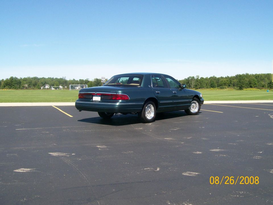 Dark green sedan parked in a lot, rear passenger side view.