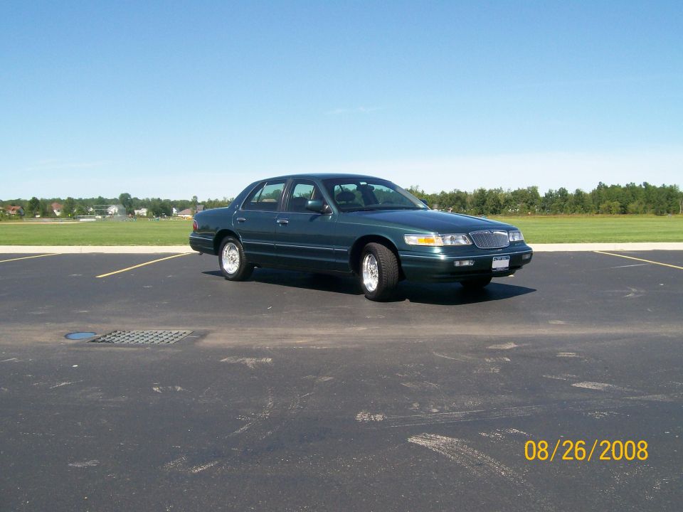 1995 Mercury Grand Marquis sedan, dark green, parked in an asphalt lot.