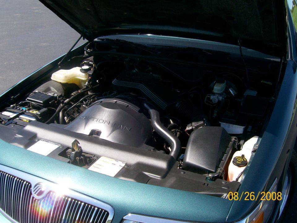 Engine bay of green Mercury sedan with hood open showing intake
