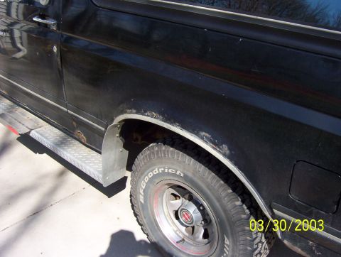1987 Ford Bronco - Close-up of a black SUV's side, revealing rust spots and a metal step below the door.