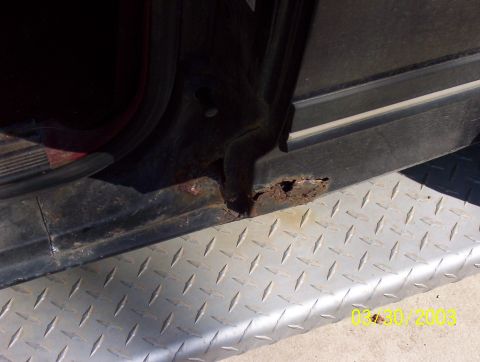 1987 Ford Bronco - Close-up of rust on a vehicle's lower body panel, with a diamond plate surface underneath.