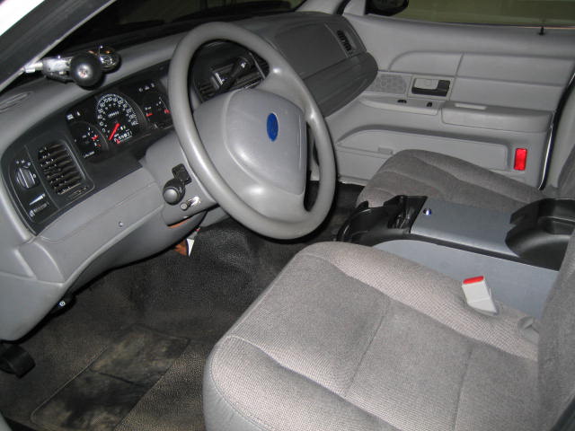 Interior of a police sedan, showing dashboard, steering wheel, and center console.