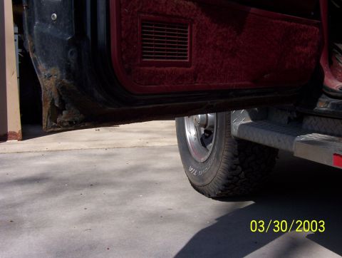 1987 Ford Bronco - The lower door panel shows significant rust damage, with a tire and running board visible.