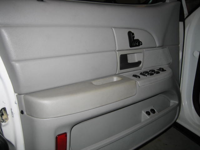 Interior car door panel with power window controls and speaker grille