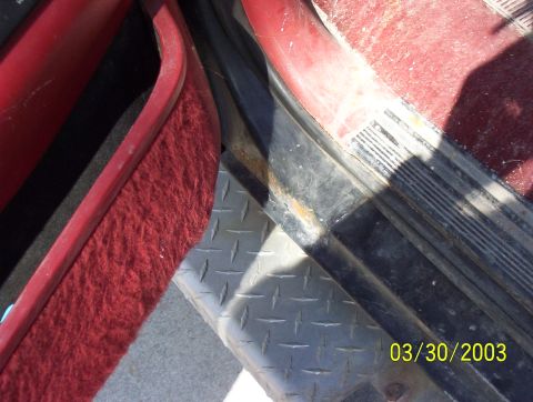 1987 Ford Bronco - Close-up of a vehicle's interior door sill, showing red carpet and diamond plate trim.