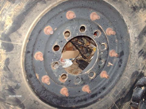 1990 Ford F-150 - A close-up view of a large, rusty lug nut assembly on a black wheel, with a portion of a tire visible on the left. The center of the wheel…