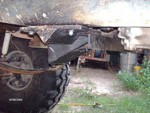 1990 Ford F-150 - A close-up view of the undercarriage of a vehicle, showing a custom-mounted bracket and suspension components, including a leaf spring and…