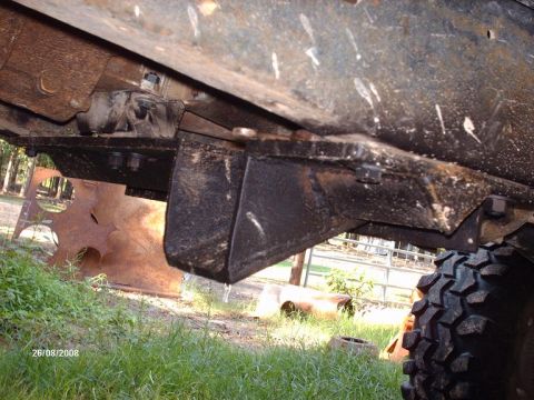 1990 Ford F-150 - A close-up, low-angle view of the undercarriage of a vehicle, showing heavy-duty metal brackets and suspension components. The scene is set…