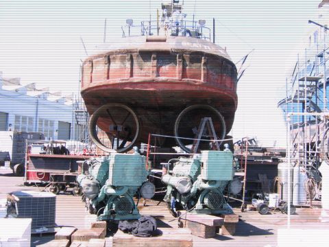 1991 Ford Bronco - A large, red, round vessel with two large propellers is elevated, with industrial engines and equipment in the foreground. The vessel appea…