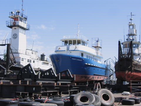 1991 Ford Bronco - A blue and white vessel named "ROBERT G. BROWNLEE" is docked in a shipyard next to another vessel. The scene is set under a clear blue sky…