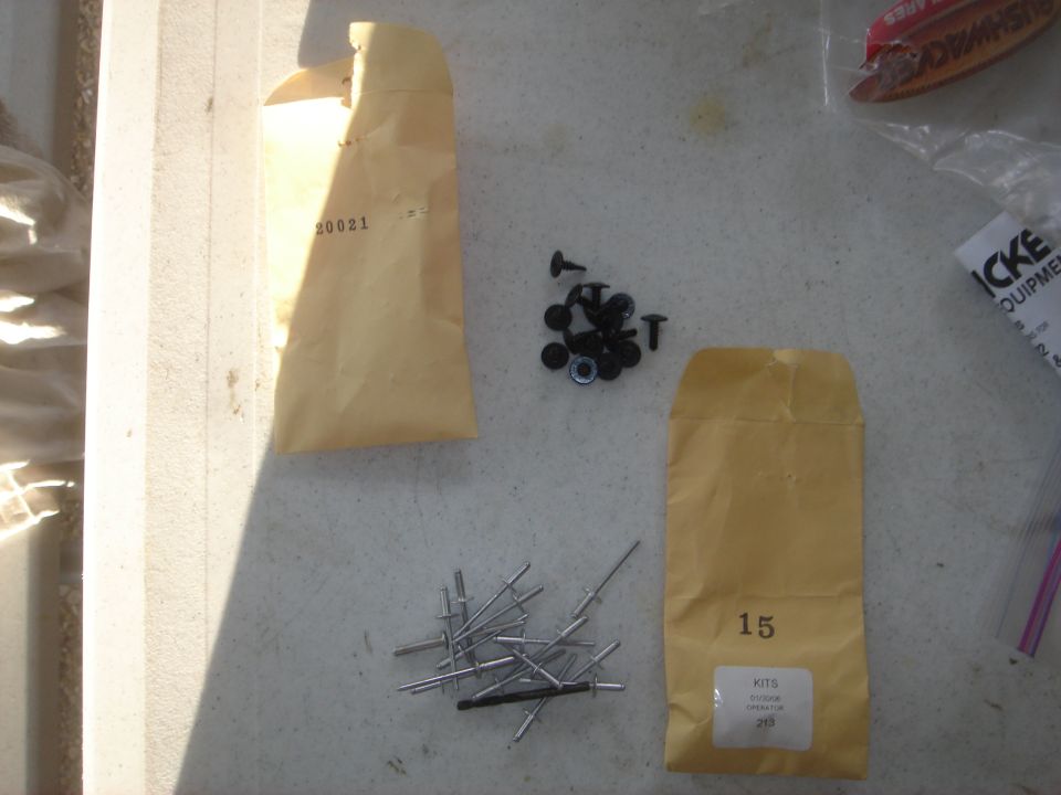 Various small parts including envelopes, rivets, and screws on a textured surface.