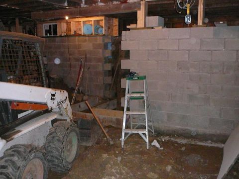 1997 Mercury Grand Marquis - This is a construction scene in a basement. A Bobcat skid steer loader is parked on the left, and a cinder block wall is under construction…