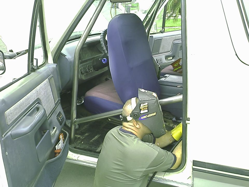 Welder working inside a Ford Bronco with a roll cage.