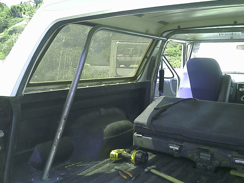 Interior of a 1990 Ford Bronco with a roll cage, tools, and a case.