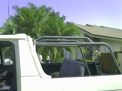 1990 Ford Bronco - The image shows the rear passenger side of a white 1990 Ford Bronco with a roll cage installed. The vehicle is parked outdoors with palm tr…