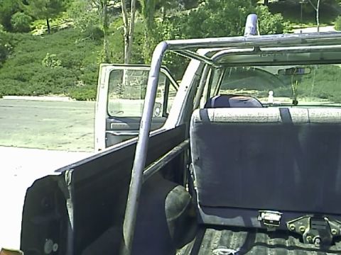 1990 Ford Bronco - The interior of a Ford Bronco is shown from the rear, looking forward. A roll bar is visible in the bed of the truck, and the rear seat is…
