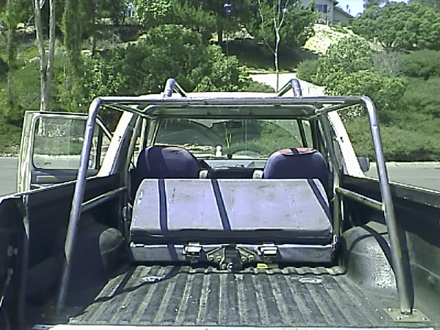 1990 Ford Bronco rear view with roll cage and cargo in bed