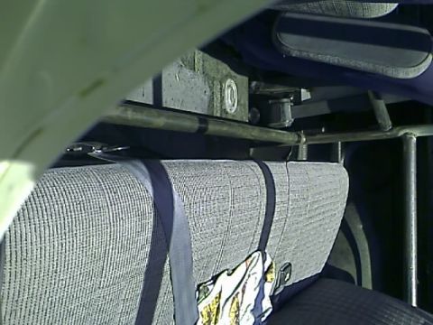 1990 Ford Bronco - The interior of a vehicle shows a close-up of a gray fabric seat with a dark blue seatbelt. Metal bars and a dark blue armrest are visible…