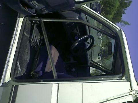 1990 Ford Bronco - The interior of a white 1990 Ford Bronco is shown with a roll cage installed. The driver's side door is open, revealing the steering wheel…