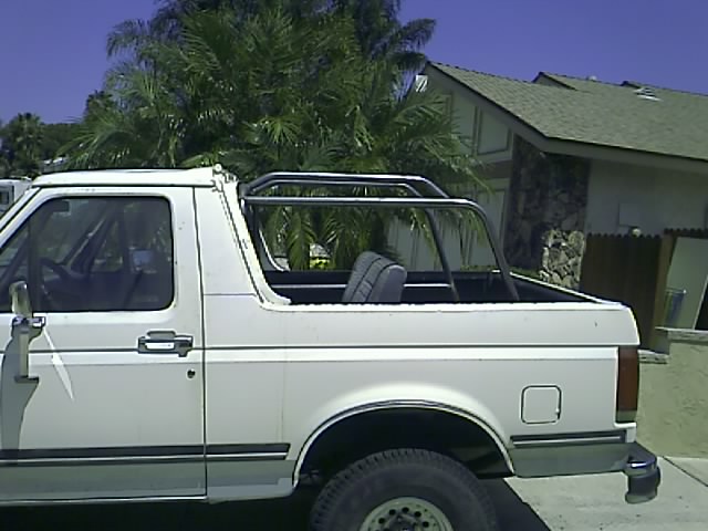 White Ford Bronco with roll cage, side view