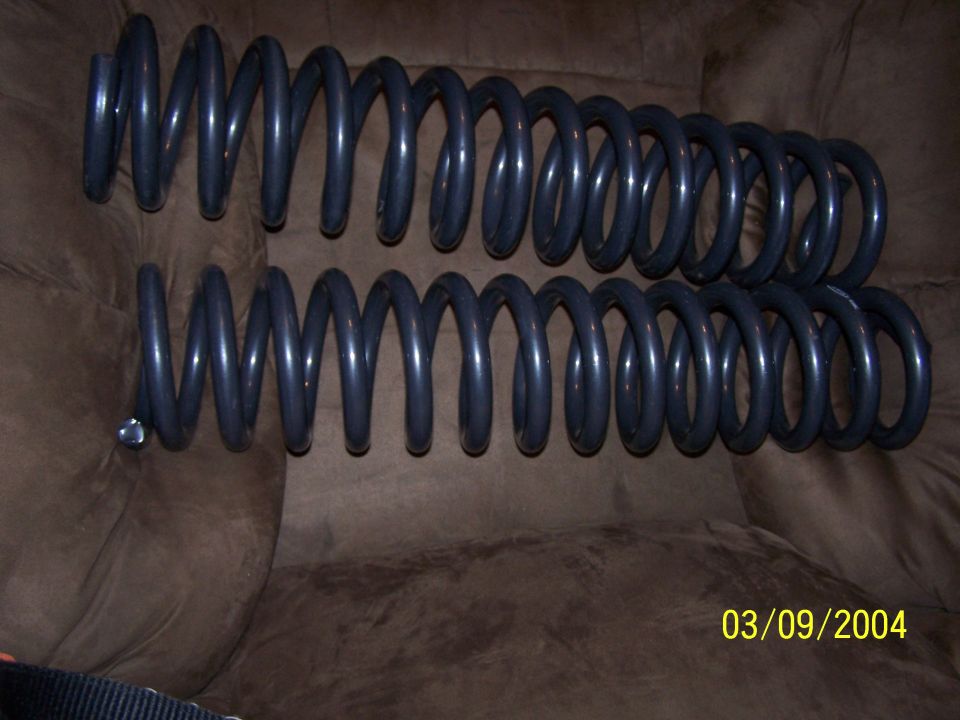 Two black coil suspension springs resting on a brown couch