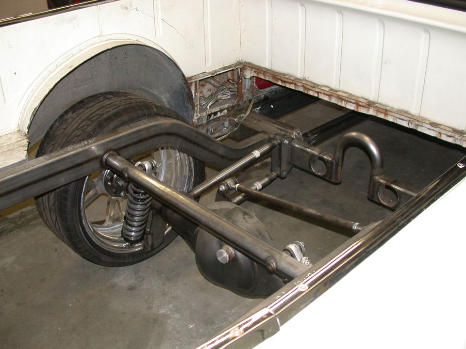 Custom tubular four-link rear suspension with coilover shock and chrome wheel under vehicle bed