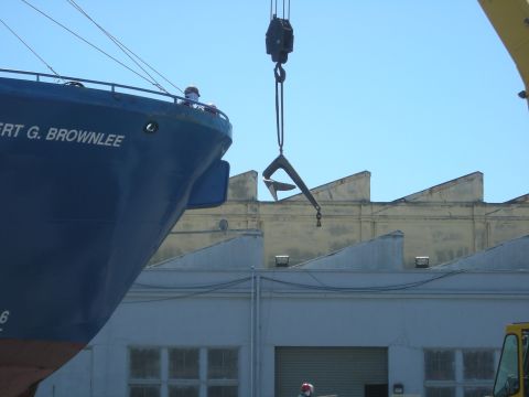 1991 Ford Bronco - A large ship is docked next to industrial buildings while a crane lifts an anchor.