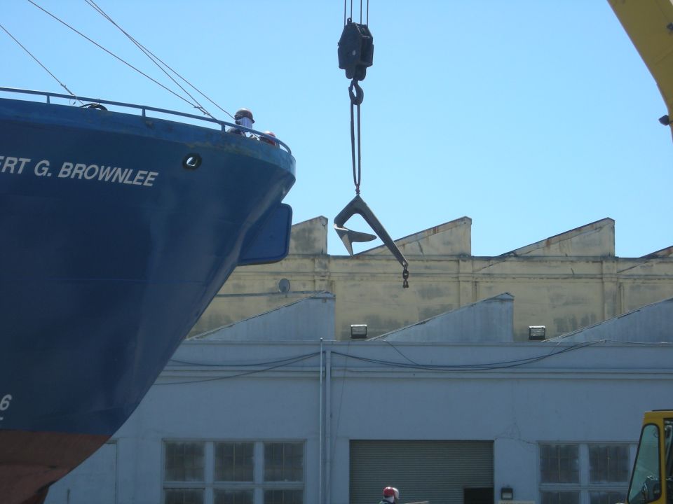 Big blue ship named 'BERT G. BROWNLEE' with a crane lifting an anchor nearby