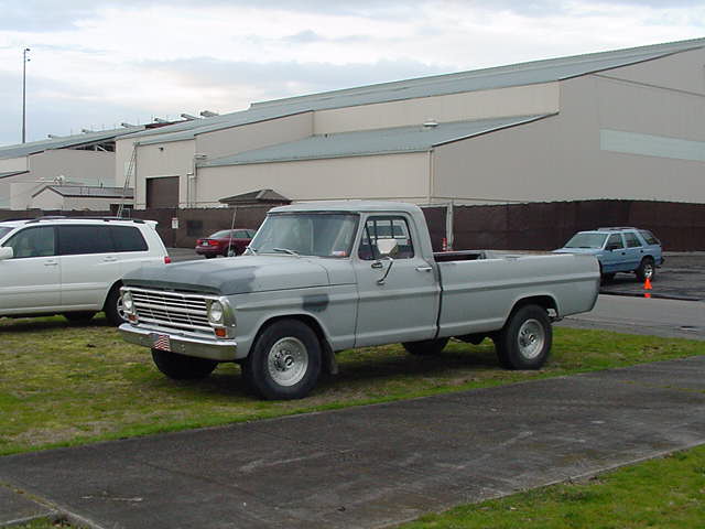 Gray vintage Ford pickup parked in an industrial lot, 3/4 front view