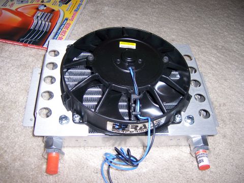 1991 Ford Bronco - A transmission cooler assembly, a fan and aluminum fins, sits on a carpeted surface next to a catalog.