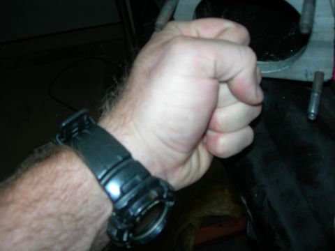 1984 Ford Bronco - A close-up shot shows a clenched fist with a black digital watch on the wrist against a dark, out-of-focus background.