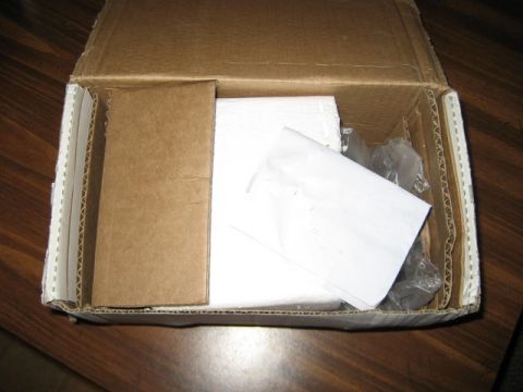 1995 Ford Bronco - Contents of a cardboard box, including paper and plastic packaging, on a wooden surface.