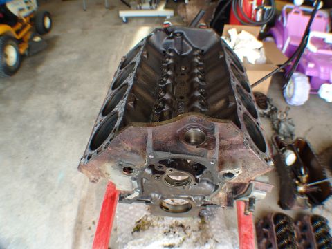 1996 Ford Bronco - Engine block on a stand, with various engine parts and a riding mower visible in the garage setting.