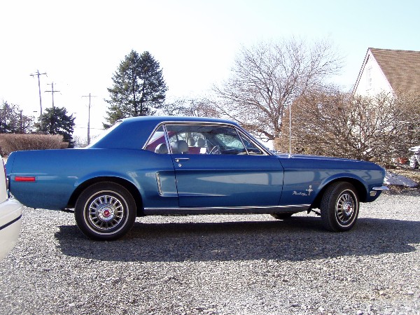 Blue 1968 Ford Mustang coupe parked on gravel, side view