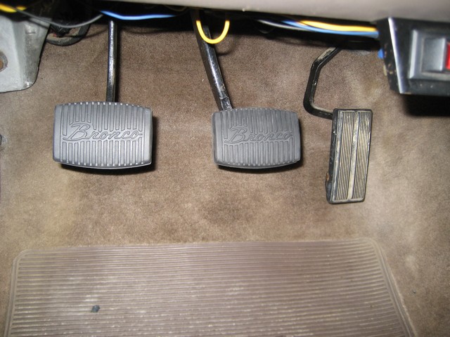 Car interior showing three pedals, two with 'Bronco' embossed, and a floor mat