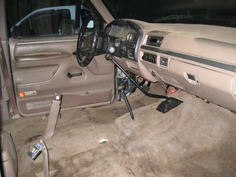 1995 Ford Bronco - Interior view of a 1995 Ford Bronco, dashboard and steering wheel visible, carpet removed from floor.