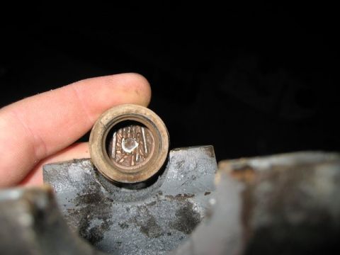 2004 Ford F-150 - A finger holds a small, circular metal component with visible internal details against a dark background.