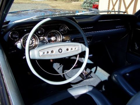 1968 Ford Mustang - The dashboard and steering wheel of a vintage automobile are shown in this interior shot.