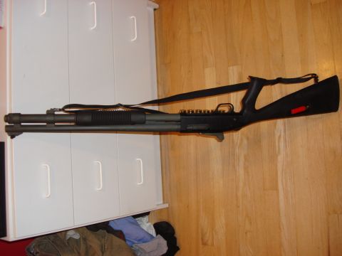 2003 Ford Crown Victoria - A shotgun is displayed against a white cabinet and wooden floor.