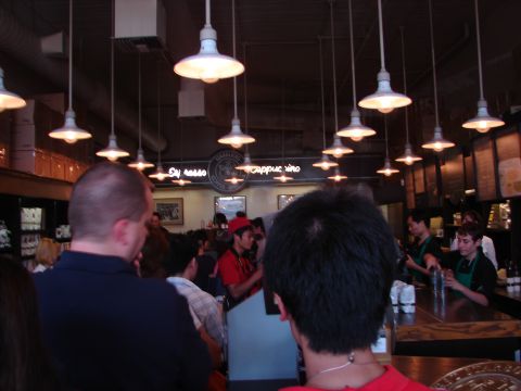 1992 Ford Taurus - A busy coffee shop interior with patrons and staff visible, under a series of pendant lights.