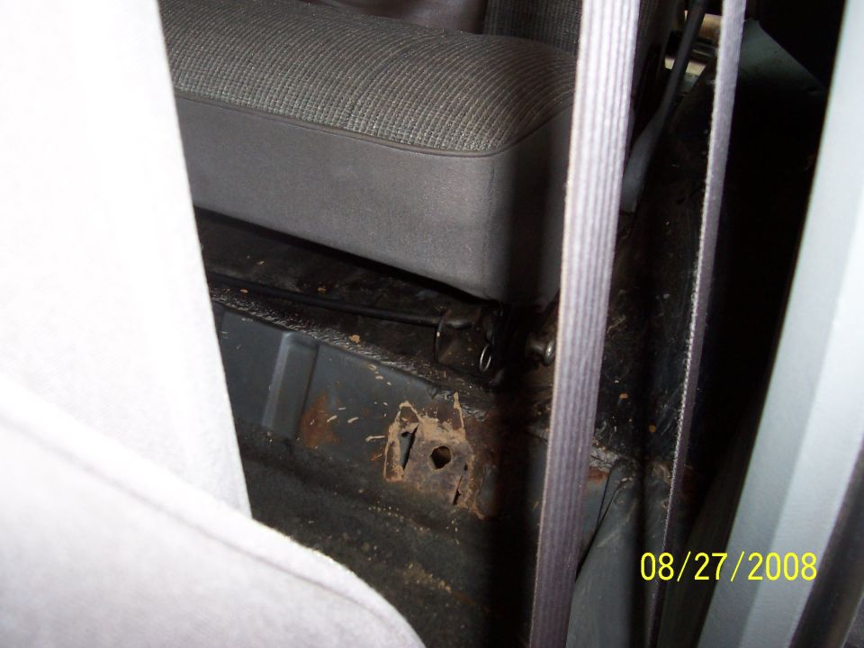 Interior view of vehicle floor pan showing rust damage near seat mounting point. Date stamp reads 08/27/2008