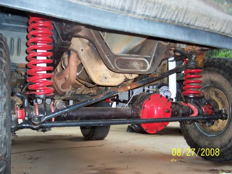 1988 Ford Bronco - The photo shows the undercarriage of a vehicle with red-painted differential covers and bright red coil springs.