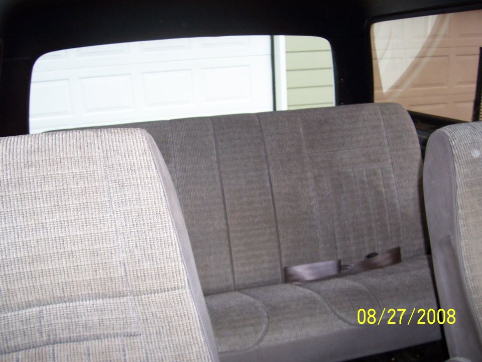 Rear bench seat with seatbelt and a garage door visible through the window