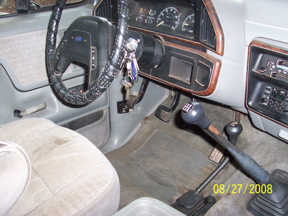 1988 Ford Bronco interior showing steering wheel, dashboard gauges, manual transmission shifter, and passenger seat